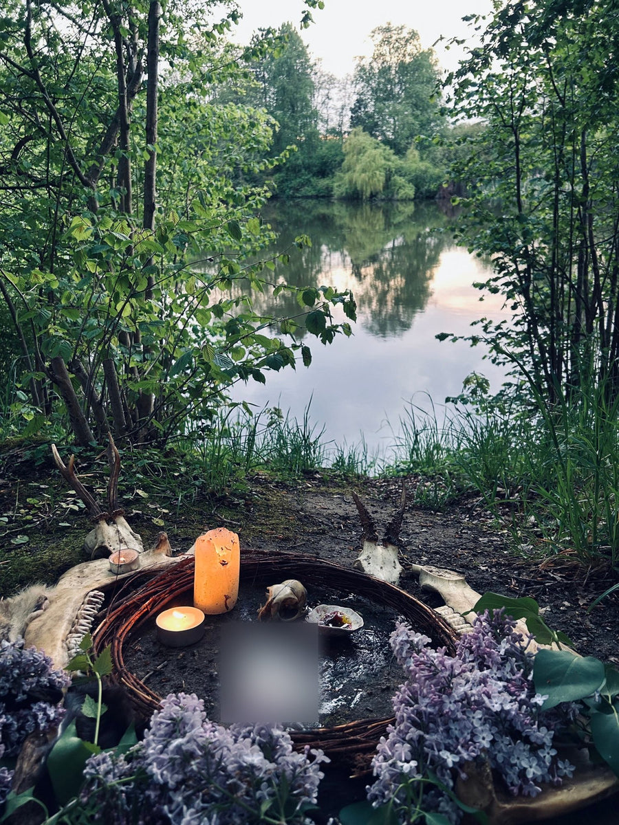Ritual circle with lilac and candles at the edge of a lake