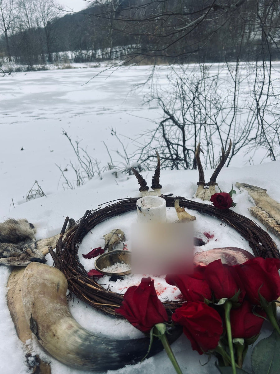 Ritual altar in the snow by a frozen lake, with antlers, a willow wreath, red roses and a horn